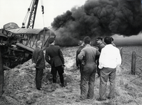 155739 Afbeelding van de ontspoorde en brandende goederentrein bij Barneveld met een groepje toekijkende NS-ers en een ...